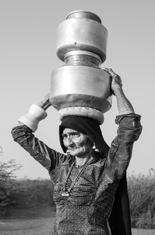 Human Right to Water in Kutch district, Gujarat - An old woman transporting potfuls of water obtained from a valve leakage on village outskirts